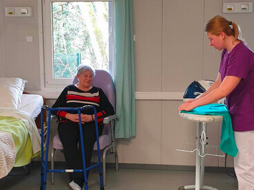 Une jeune fille fait preuve de professionnalisme et de bienveillance lors de la prise en charge de Claudine Thouraine qui joue le rôle d'une personne âgée avec une perte d'autonomie